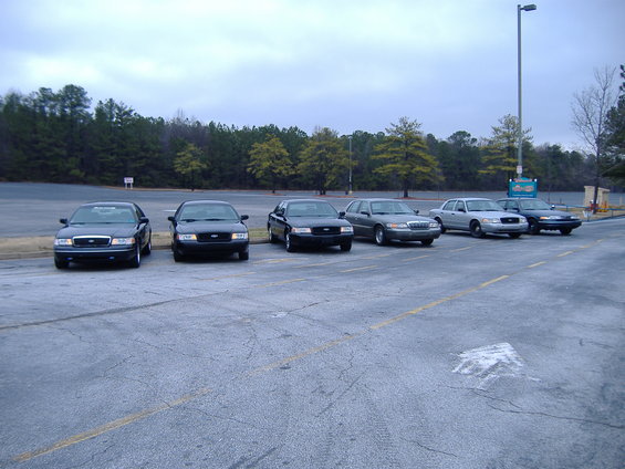 Six Ford Crown Victorias parked in a lot, front view