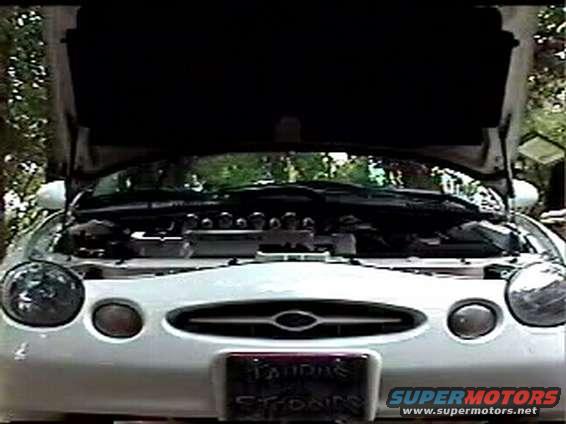 1997 Ford Taurus front view, hood open showing engine bay. License plate visible