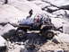 1989 Ford Bronco - A modified off-road vehicle tackles a challenging rocky obstacle course with people inside.