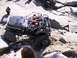 1989 Ford Bronco - An off-road vehicle with a roll cage is driven over large rocks, with another vehicle visible in the background.