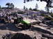 1989 Ford Bronco - A group watches as a custom off-road vehicle tackles a challenging rocky terrain under a clear sky.