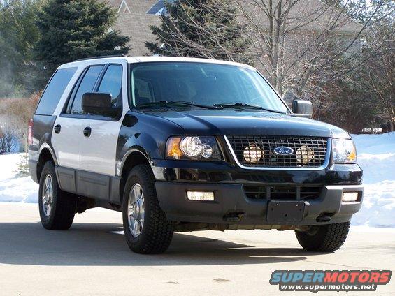 Black and white Ford Expedition SUV with grille lights, parked on a driveway in front of a house