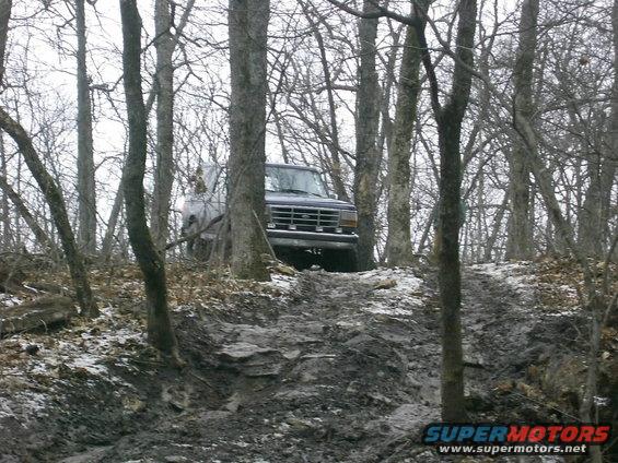 Dark SUV on a muddy, wooded trail