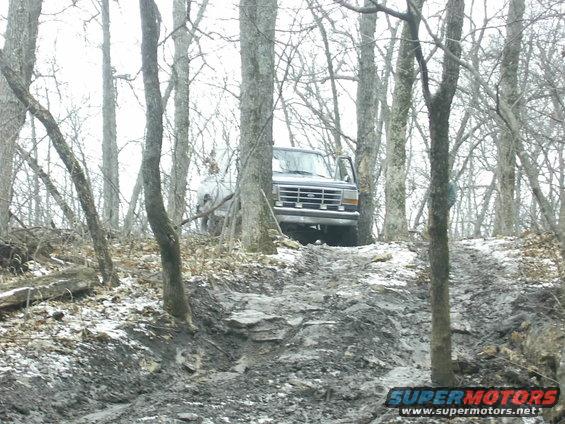 Dark gray Ford Bronco on a muddy, wooded trail