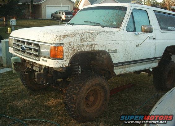 White 1987 Ford Bronco with mud splatter and lifted suspension