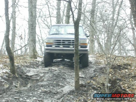 Ford Bronco driving on a muddy, wooded trail