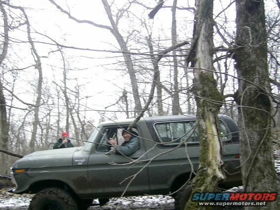 Gray 1978 Ford Bronco driving off-road through trees