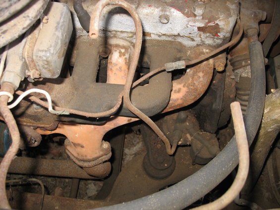 Engine exhaust manifold with rusty pipes and hoses