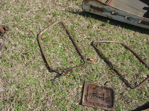 Two metal frames and a rectangular plate with a handle, lying on grass