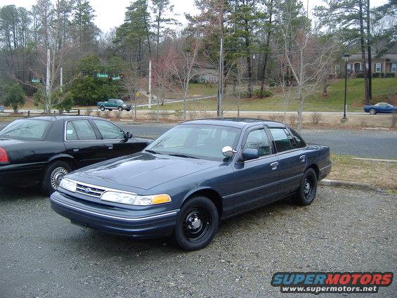 Blue 2001 Ford Crown Victoria parked next to a black Ford Crown Victoria