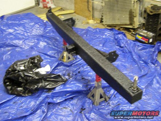 Black rear bumper and trailer hitch assembly on blue tarp