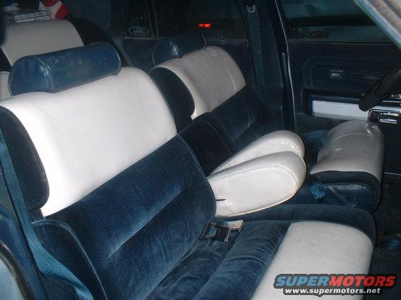 Interior view of a car with blue velvet and white seats. Seatbelts are visible