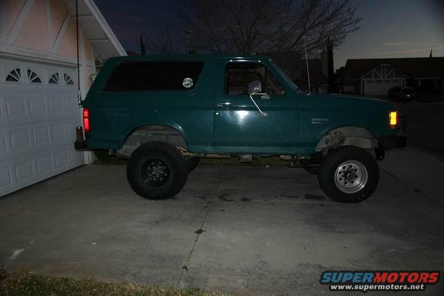 Green 1991 Ford Bronco parked next to a garage