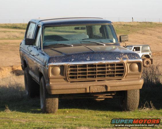 Front view of a muddy 1978 Ford Bronco with a brown grille and bumper