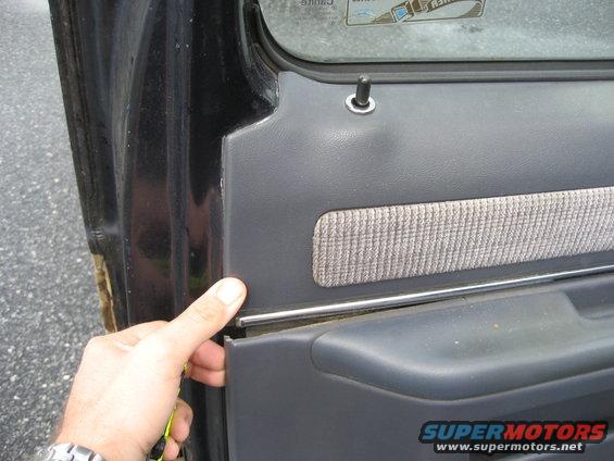 Hand removing a dark gray door panel with a textured fabric insert from a vehicle interior
