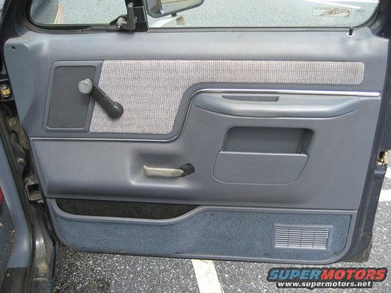 gray and blue truck door panel with manual window crank and door handle