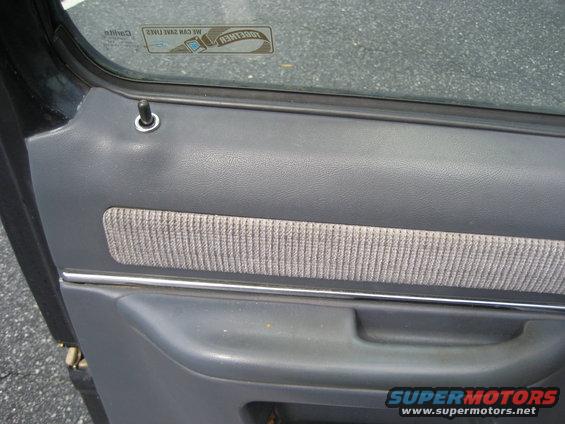 Gray car door panel with fabric insert and chrome trim