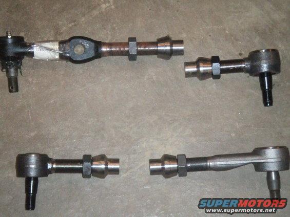 four steering linkage components laid out on concrete floor