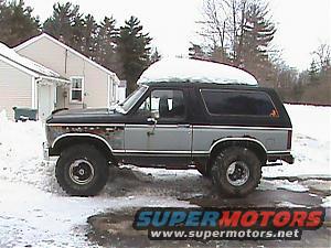 1980s Ford Bronco with snow on roof parked in a snowy driveway