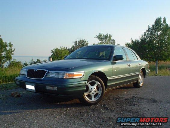 1996 Mercury Grand Marquis, green, parked on asphalt near water and trees