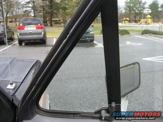 View from inside a vehicle looking out the door frame at a side mirror and other cars in a parking lot