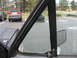 1981 Ford Bronco - Close-up of a vehicle's door frame and side mirror with other vehicles visible in the background.