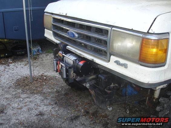 Front of a white Ford truck with a winch mounted on the bumper. Has 4x4 badging