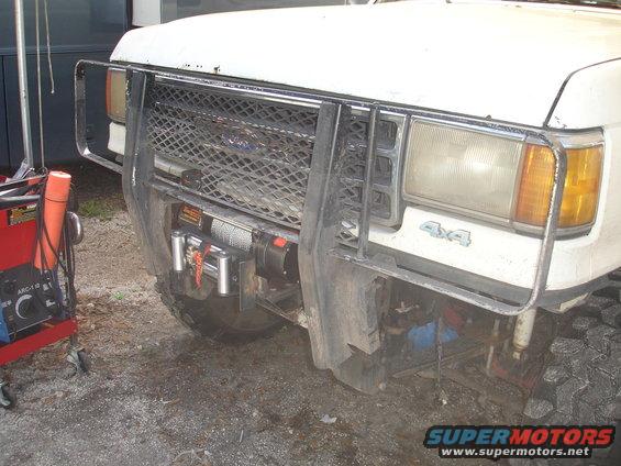 White Ford Bronco front end with a winch mounted behind a brush guard. The grille has a diamond pattern. "4x4" emblem is visible