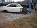 1963 Ford Galaxie - A white sedan, stripped of its front end, is parked on a gravel lot with a tow truck in the background.