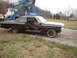 1963 Ford Galaxie - A black 1963 Ford Galaxie coupe, stripped of its interior, is positioned next to a tow truck.