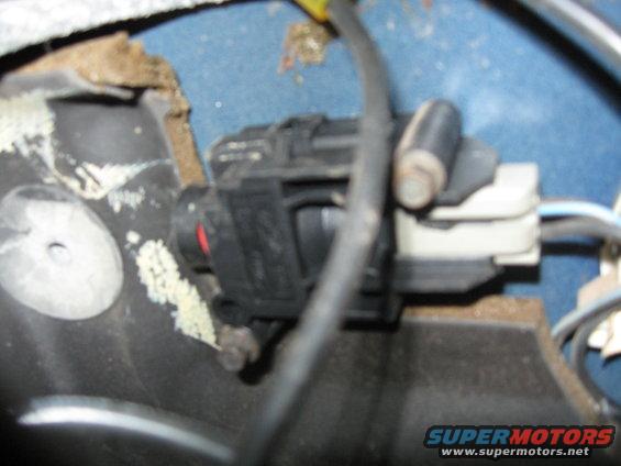 close-up of a black electrical connector with wires attached, mounted on a blue surface