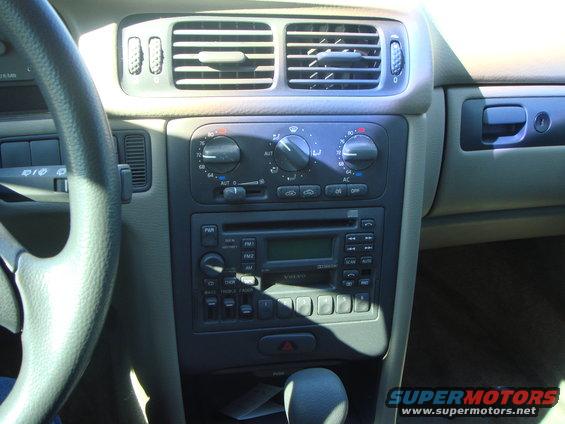 Car interior showing dashboard, steering wheel, air vents, radio, and gear shifter