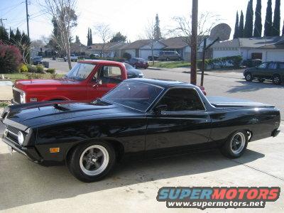 black 1970 Ford Ranchero parked on driveway, red pickup truck behind it