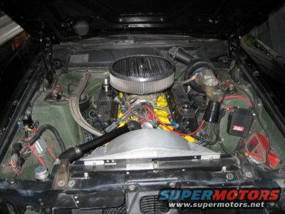 Engine bay with V8 engine, chrome air cleaner, yellow valve covers, and aftermarket ignition. Visible SuperMotors logo