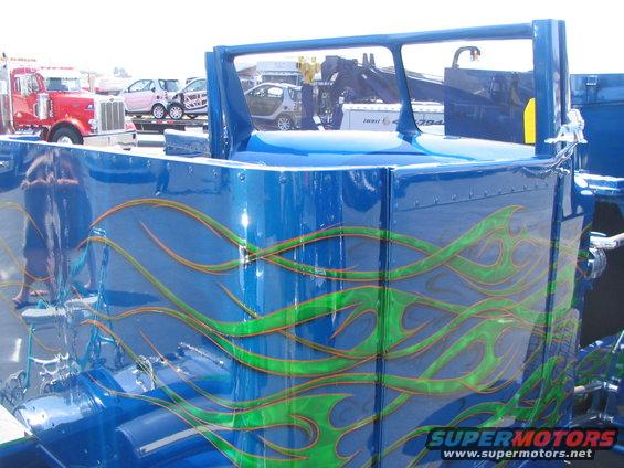 Blue truck cab with green and orange flame graphics. Other vehicles visible in background