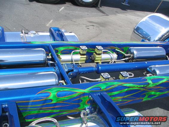 Blue chassis with green flames, chrome air tanks, and yellow air compressors