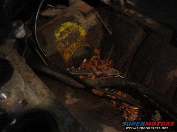 Engine bay with debris, wires, and a yellow-marked metal component