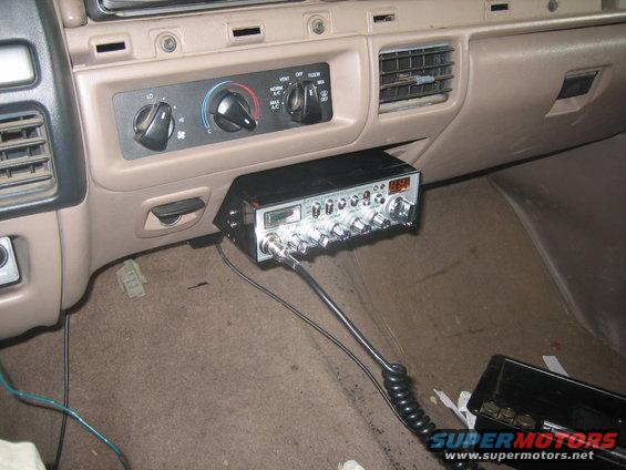 CB radio mounted below dashboard air vents, with coiled cord and microphone