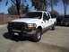 2000 Ford F-250 - A white Ford pickup truck with a tan lower body is parked on a concrete surface, with other vehicles in the background.