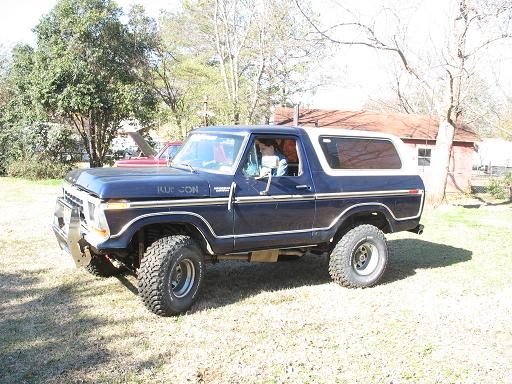 Dark blue 1978 Ford Bronco with a white top, parked on grass. Chrome bumper and trim are visible