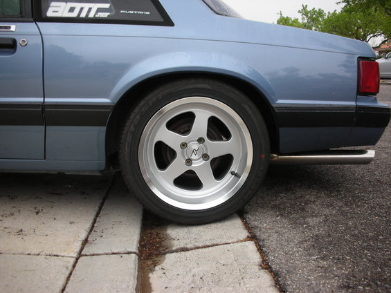 Blue 1990 Ford Mustang rear quarter panel with aftermarket wheel and exhaust