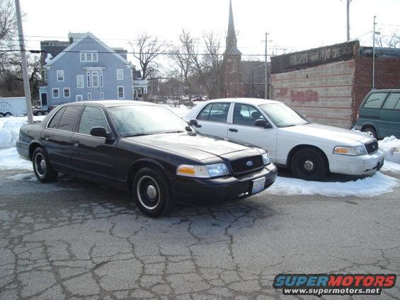 Black 2000 Ford Crown Victoria police car parked next to a white one