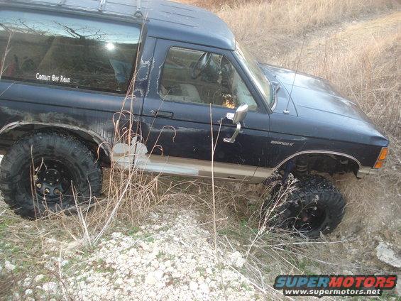 1989 Ford Bronco II with off-road tires on uneven terrain. 'Cobalt Off Road' sticker on the rear window