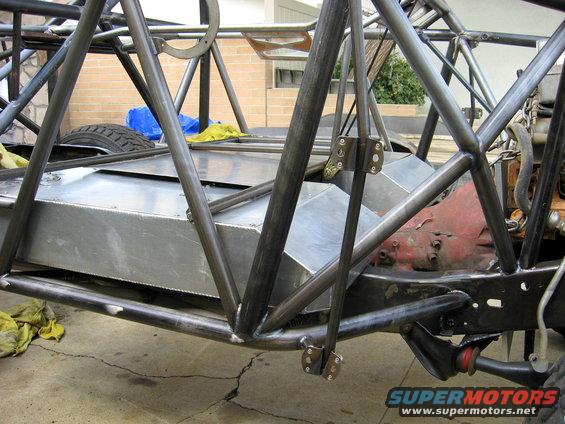 Custom race vehicle chassis under construction, showing a large metal fuel tank and roll cage tubing
