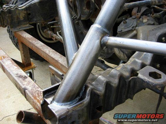 Custom roll cage welded to vehicle frame, showing suspension components