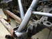 1995 Ford Bronco - Close-up view of a custom roll cage being fabricated and welded onto a vehicle's frame, with suspension parts visible.