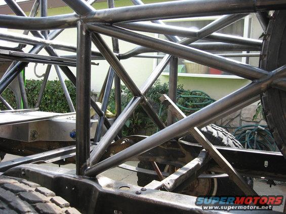 Roll cage and chassis of a vehicle under construction, with visible tires and suspension components