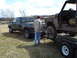 2008 International School Bus - A man stands between a pickup truck and a trailer carrying a heavily damaged vehicle.