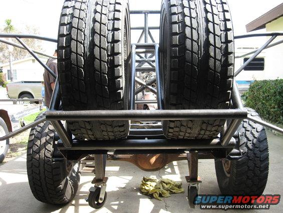 Rear view of a custom off-road vehicle with two spare tires mounted vertically on a metal rack