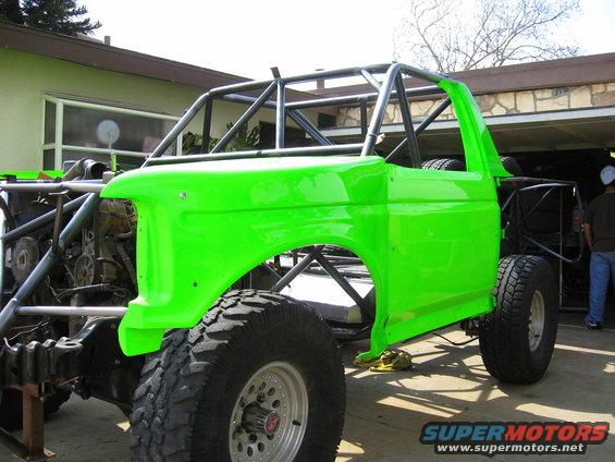 Custom buggy frame with bright green Ford Bronco body panels, roll cage, and large off-road tires